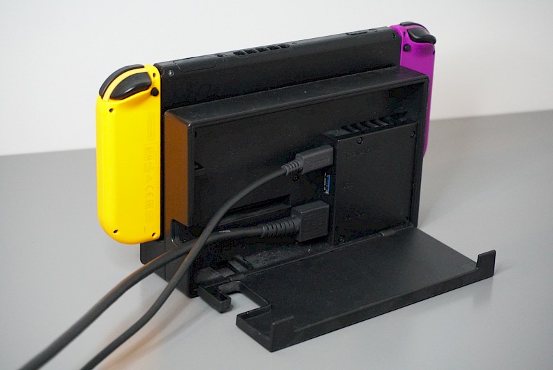 Die Nintendo Switch von hinten im TV-Modus. Sie ist in die Station gesteckt und die zwei Kabel sind verbunden.