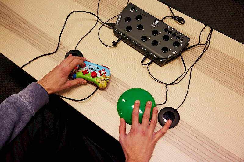 Der Hori Flex Controller. 4 Externe Taster und ein Controller sind angeschlossen. Ein Jugendlicher bedient die Tasten.