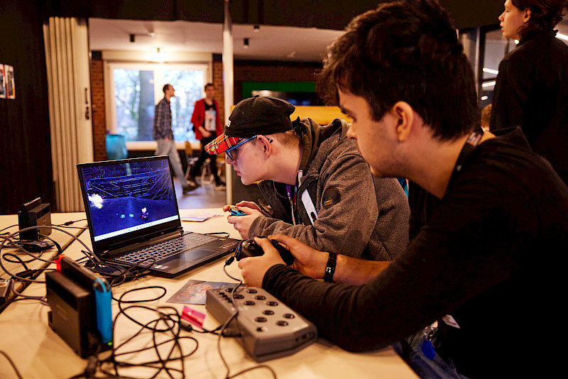 Zwei Jugendliche spielen vor einem Laptop mit Controllern.