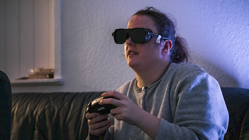 Eine Jugendliche hat eine Simulations-Brile auf. Sie spielt ein Game.