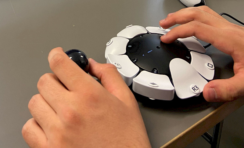Eine Person spielt mit dem Access Controller. Sie hat die linke Hand am Joystick und die rechte Hand auf den Tasten.