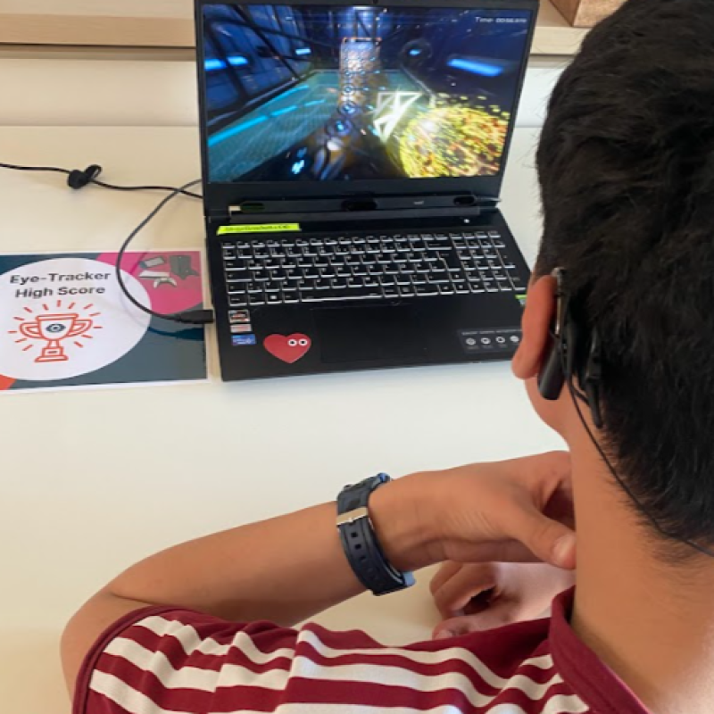 Ein Jugendlicher mit dunklen Haaren und Cochlea Implantat spielt mit einem Eyetracker am Laptop Mindball.