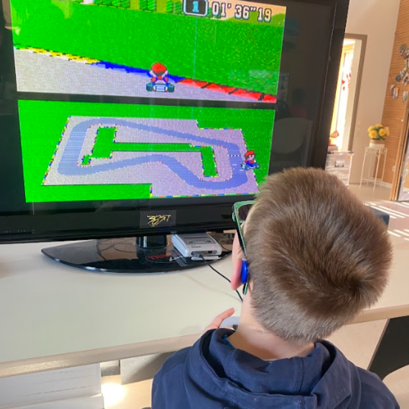 Ein Jugendlicher sitzt vor einem Fernseher. Er spielt Super Mario am SNES.