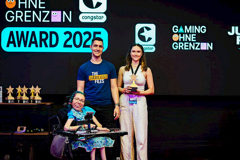 Ein Foto von den Gewinner*innen von Award National: The Darkest Files. Cenk Melzer ist Programmierer. Hanna Scheck ist Künstlerin und Managerin für die sozialen Medien. Die Laudatorin Melanie Eilert ist auch auf dem Foto.